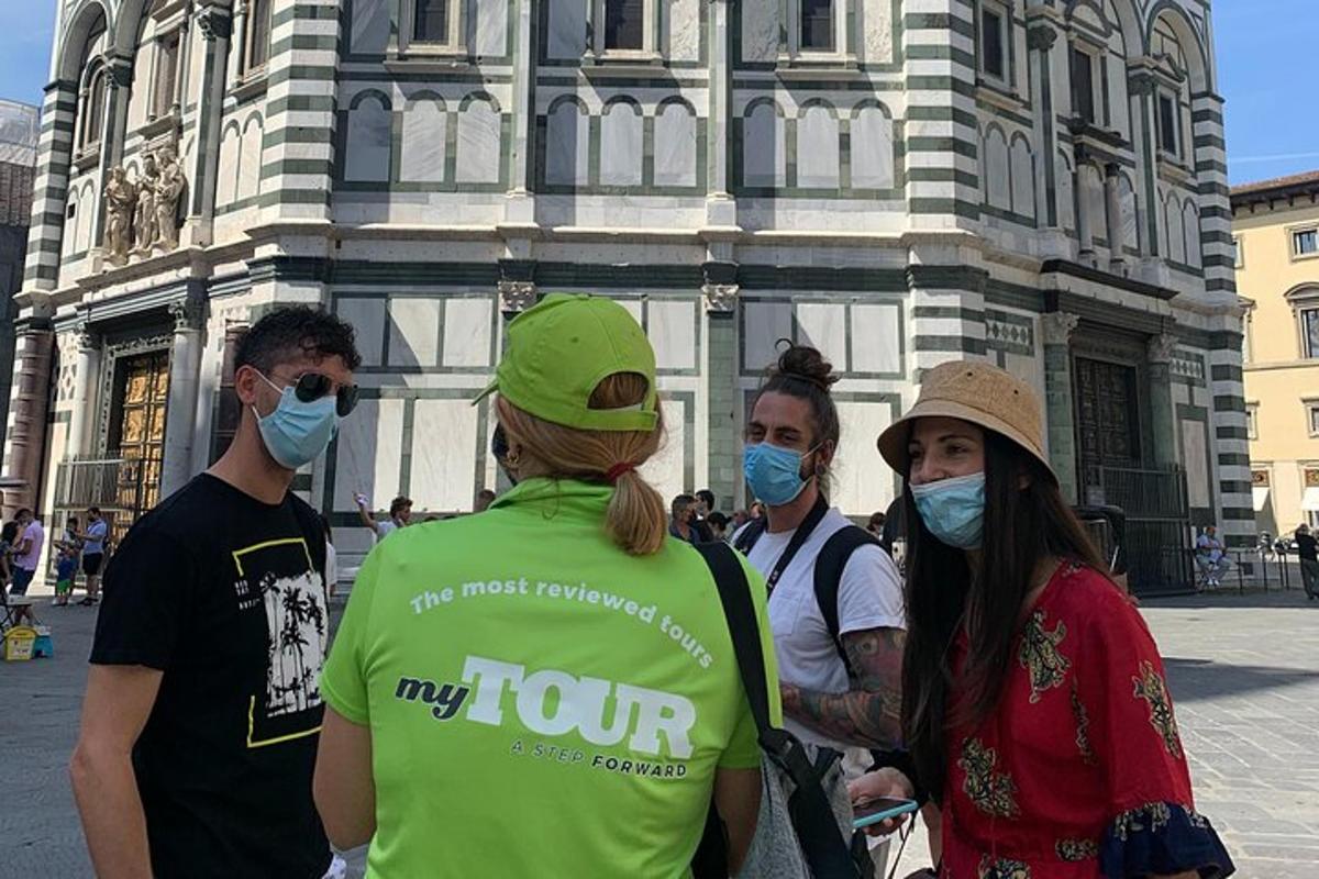 un gruppo di persone che indossano mascherine davanti a un edificio