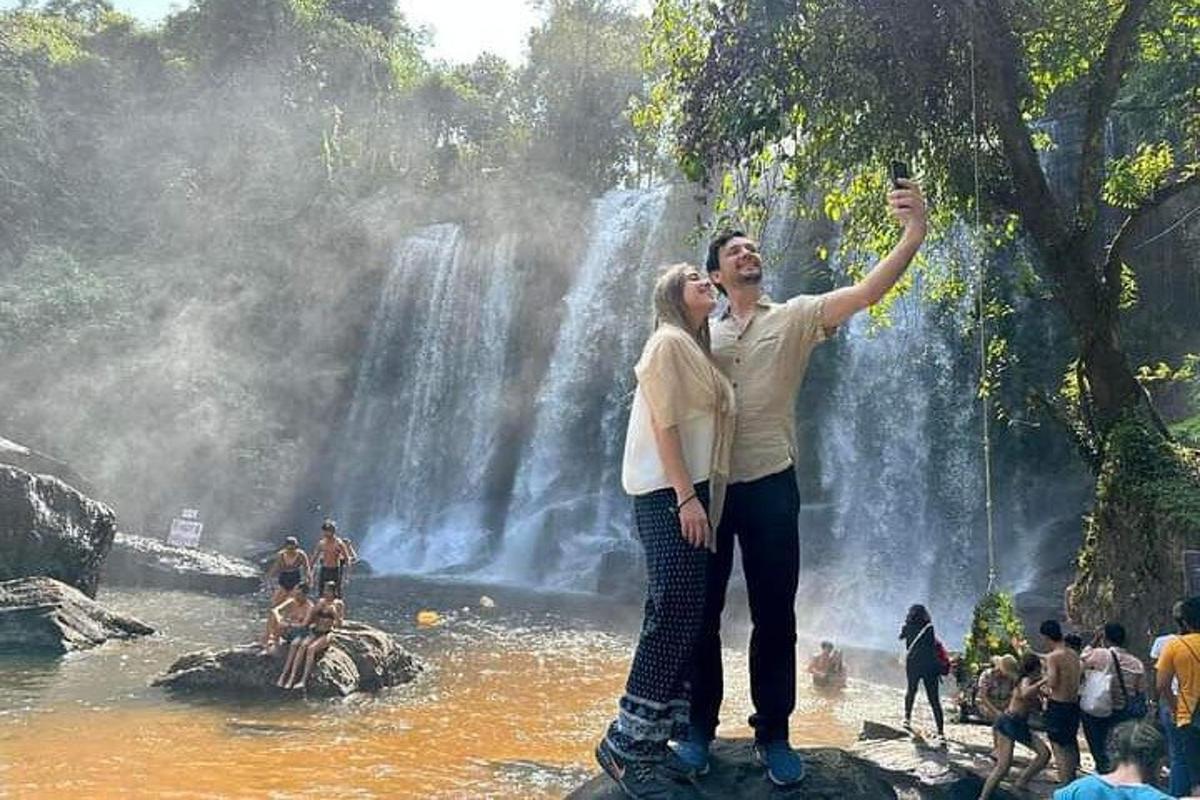 un uomo e una donna in piedi davanti a una cascata