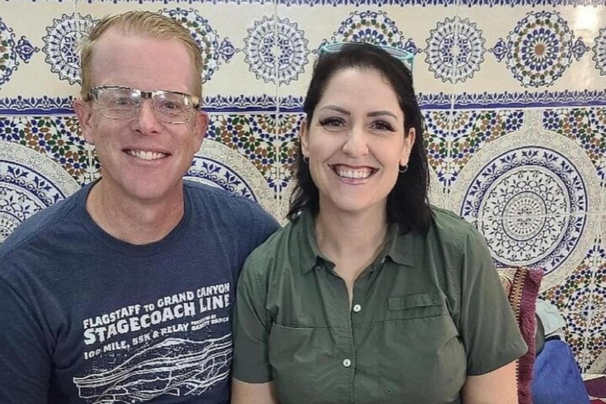 um homem e uma mulher em pé em frente a uma parede