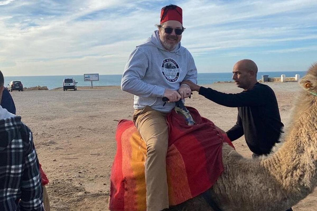 um homem sentado em um camelo na praia