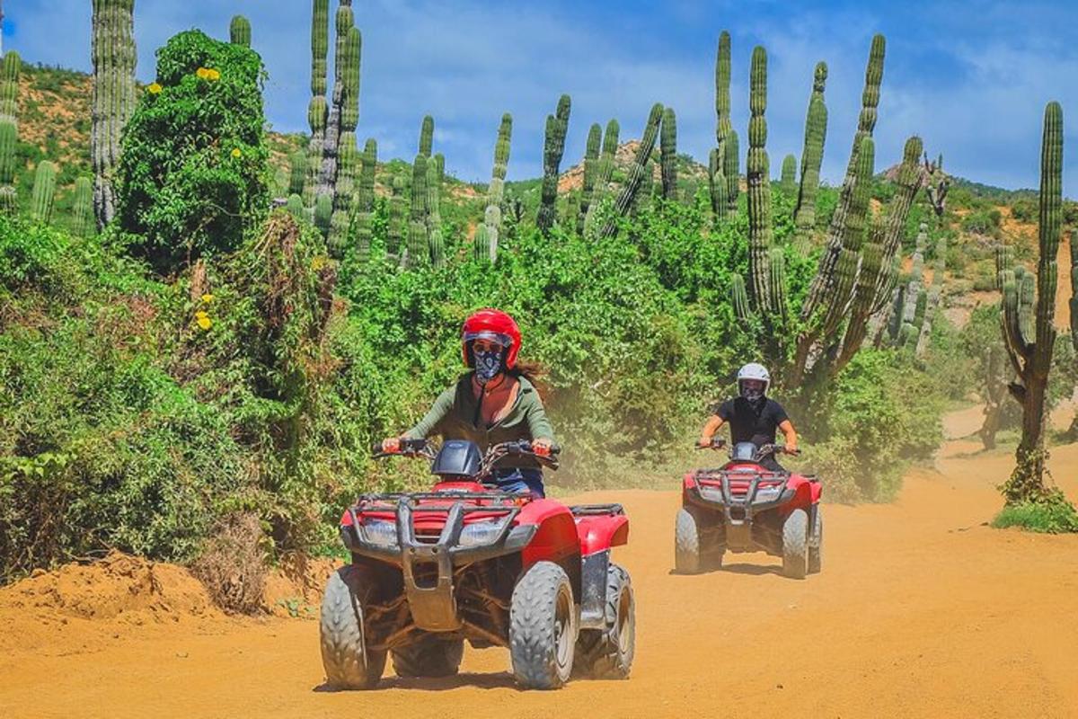 due persone che guidano un quad su una strada sterrata