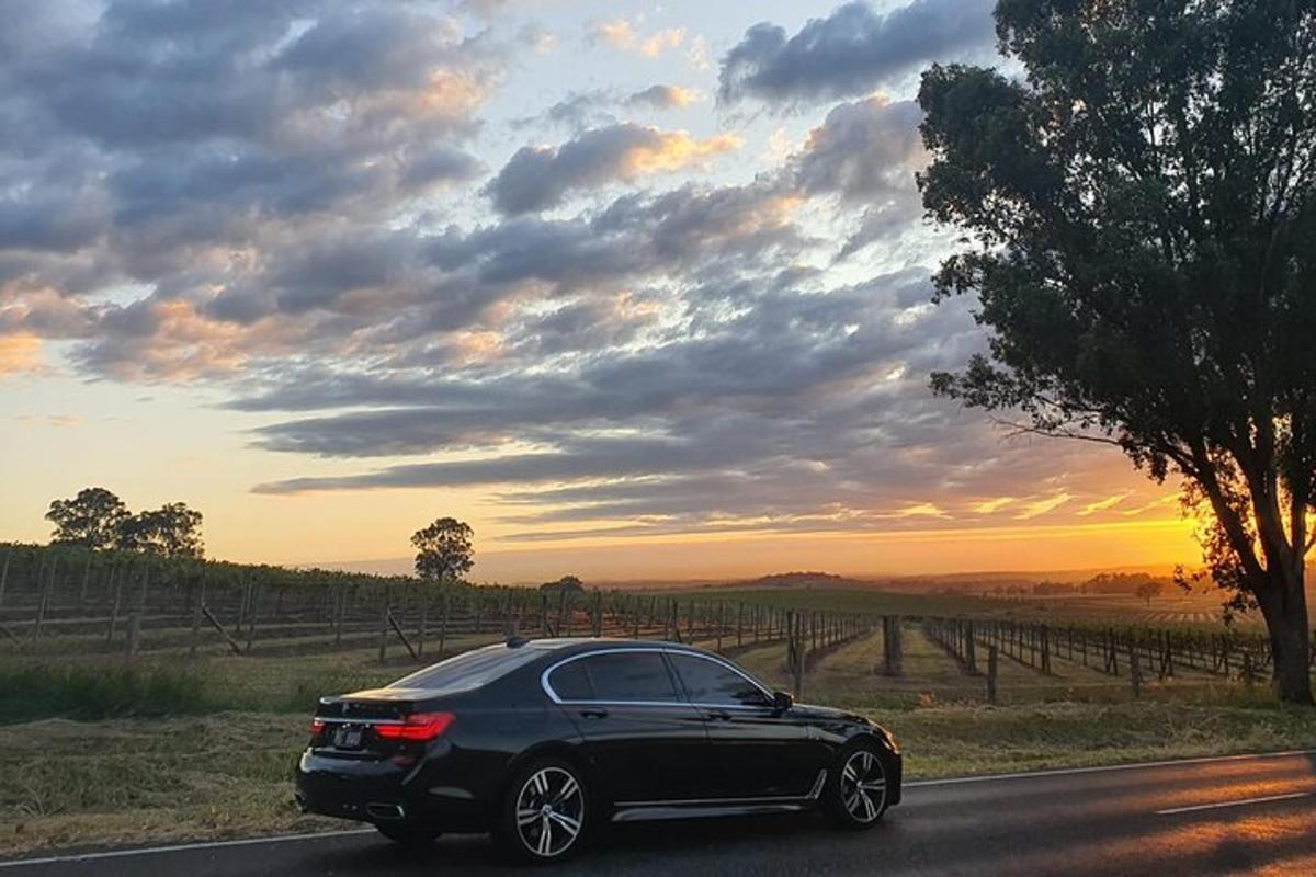 une voiture noire roulant sur une route avec un coucher de soleil