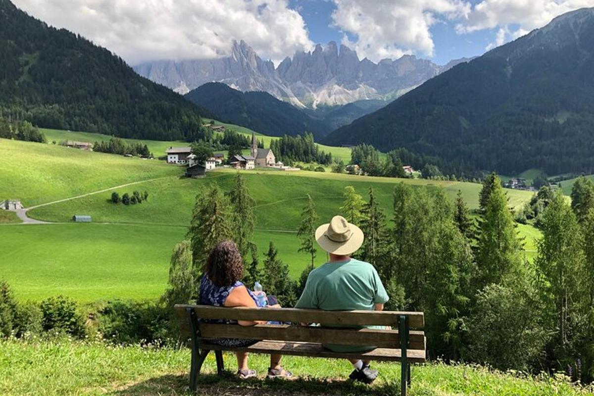 a man and woman sitting on a bench looking at the mountains