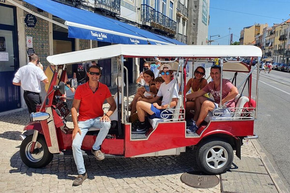 skupina lidí jedoucích na červenobílém golfovém vozíku