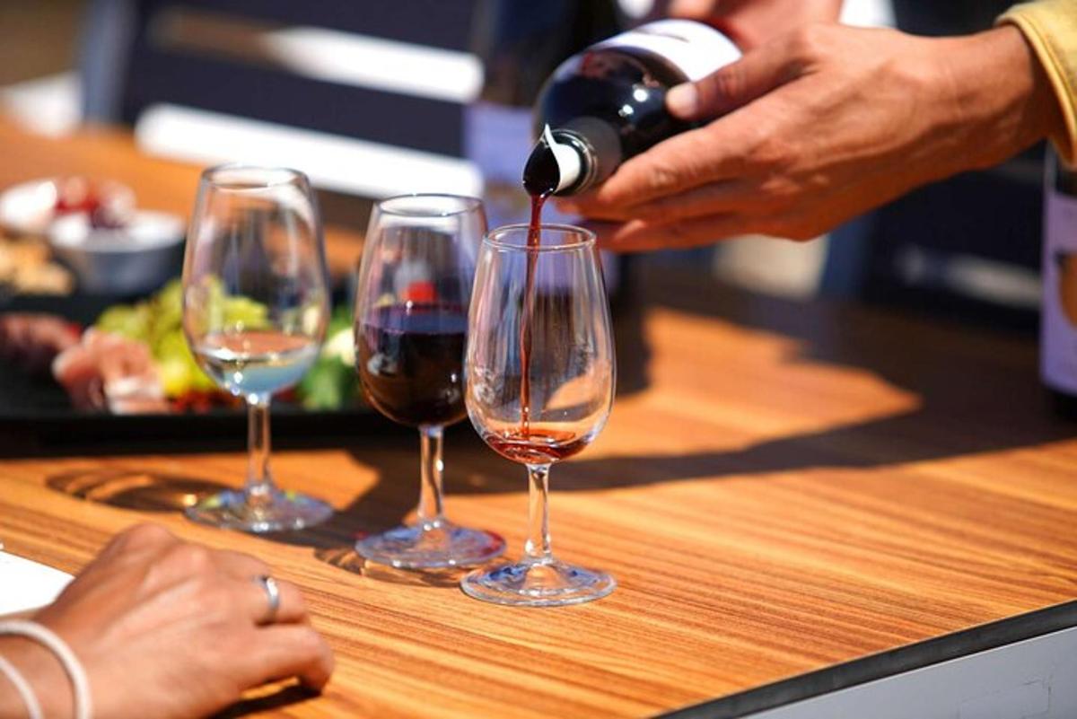 a person pouring wine into three wine glasses