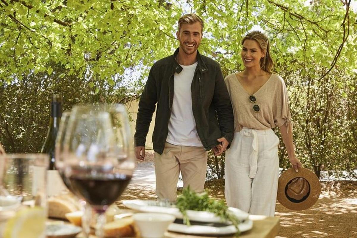 un uomo e una donna in piedi accanto a un tavolo con bicchieri di vino