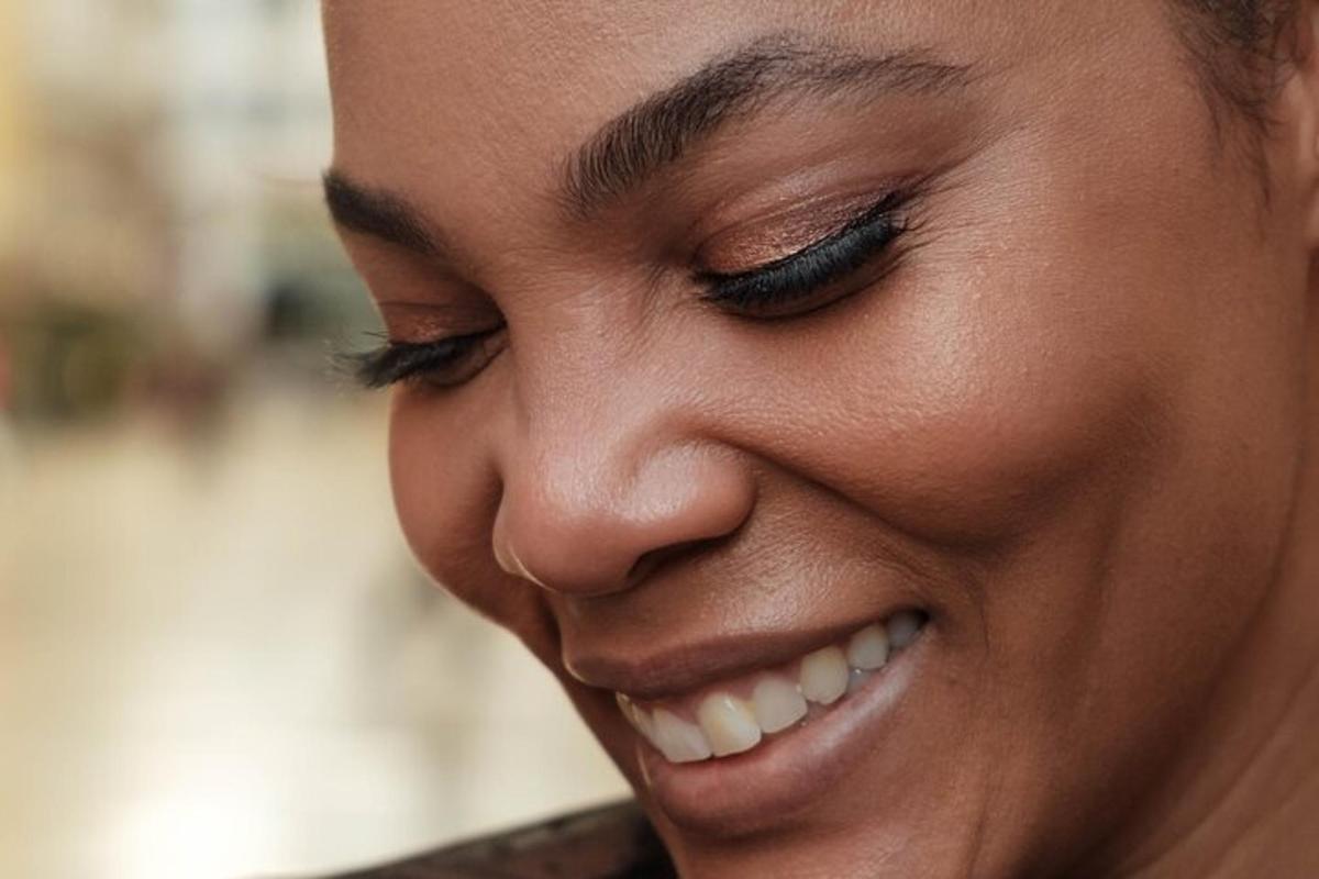 Una mujer sonriendo con los ojos cerrados y escribiendo