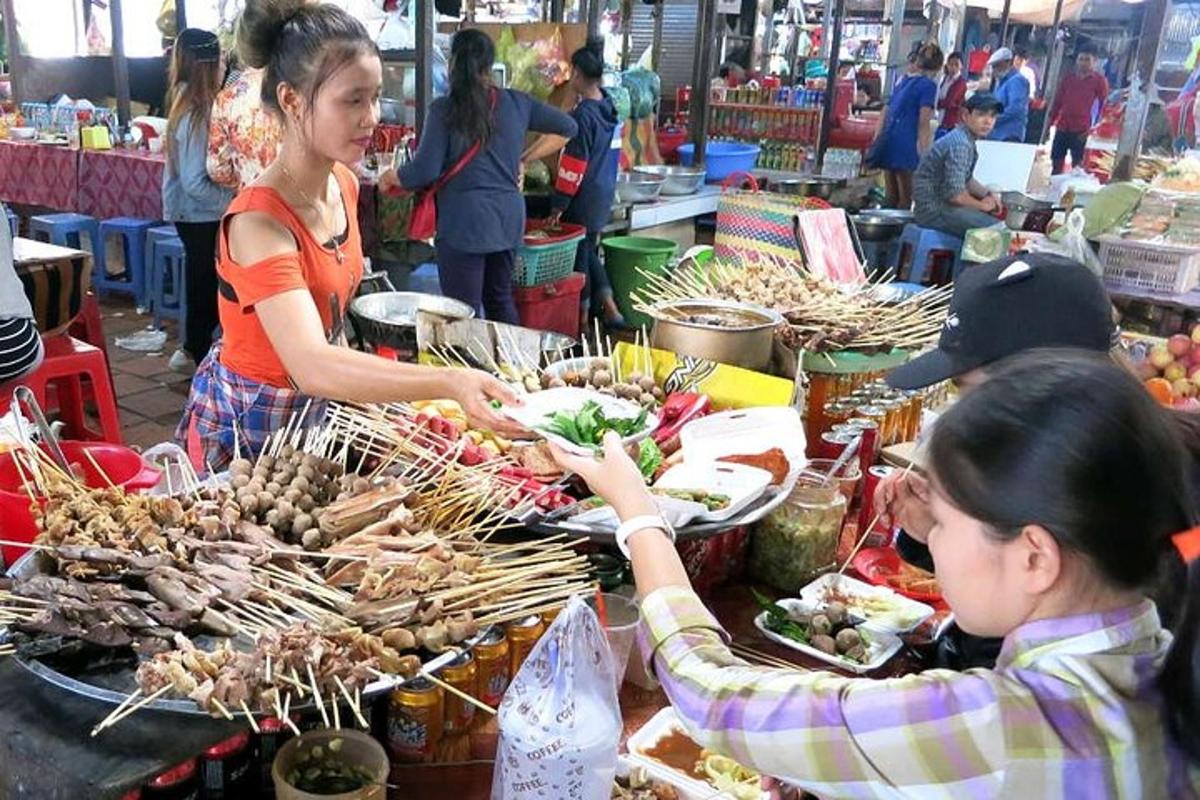 una donna che porge un piatto di cibo a un'altra donna al mercato