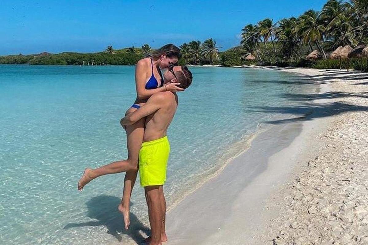 un uomo che porta in braccio una donna su una spiaggia
