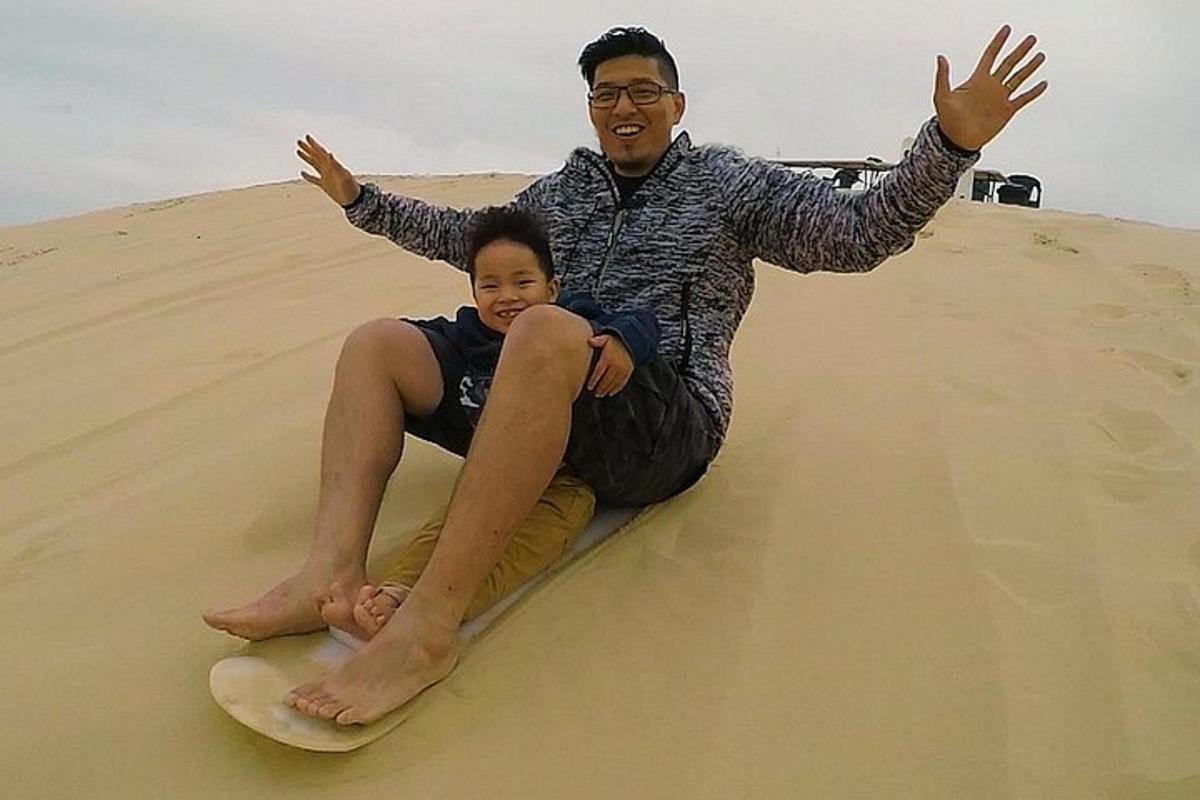 a man and a woman sitting on a surfboard in the sand