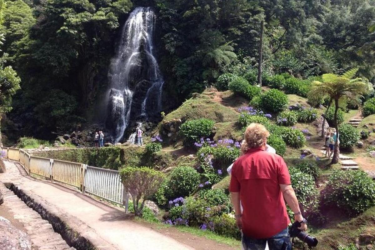 un home caminant cap a una cascada en un jardí