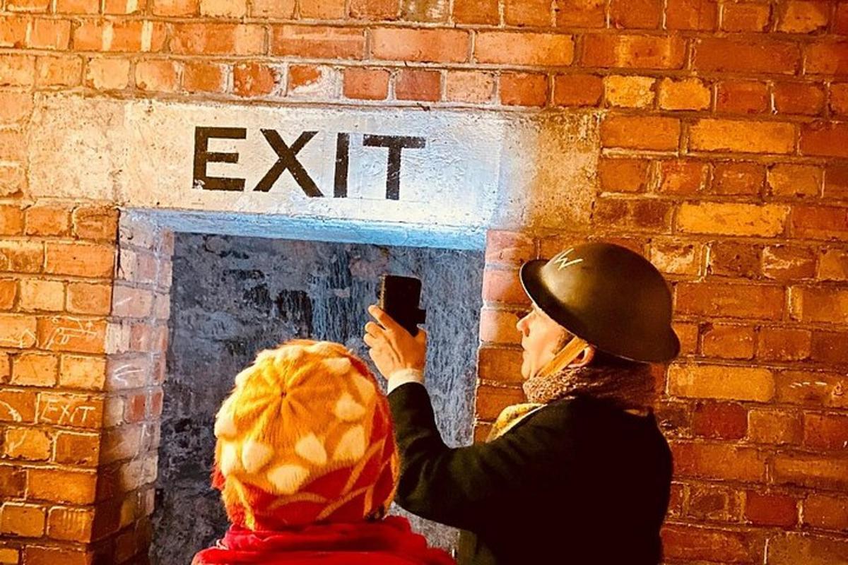 a woman taking a picture of an exit sign on a brick wall