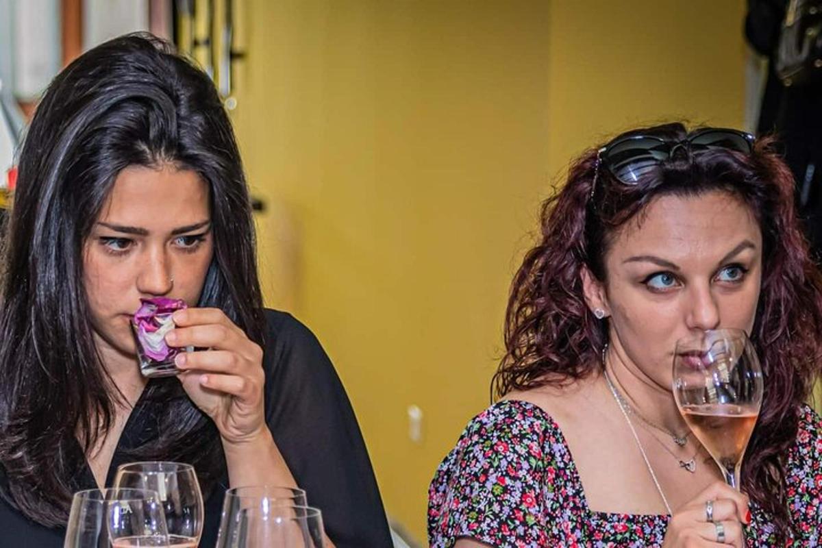Dve ženski pijeta vino iz kozarcev za vino