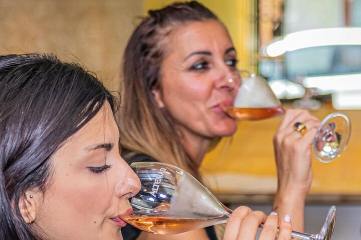 Dve ženski pijeta vino iz kozarcev za vino