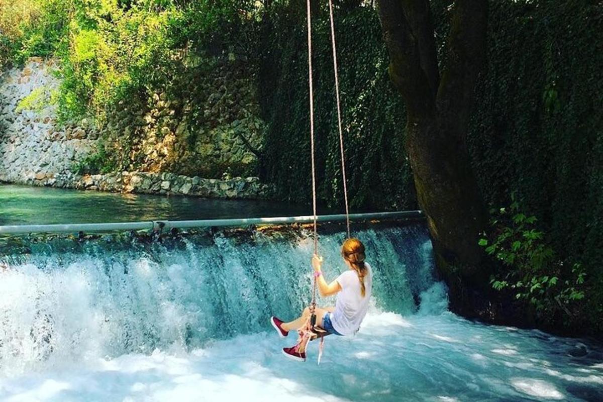a woman on a swing in front of a waterfall