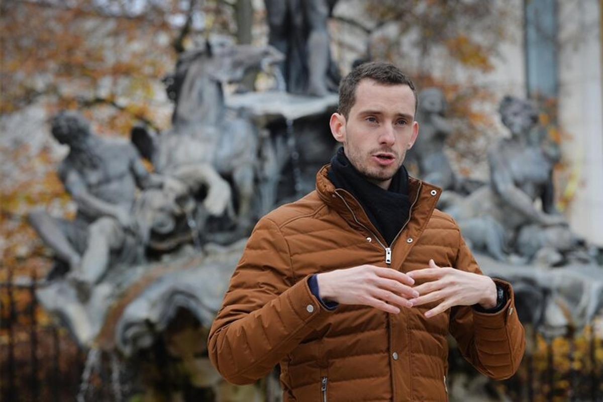 a man in a brown jacket standing in front of a fountain