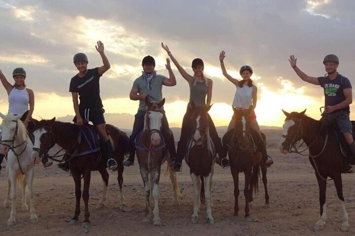 a group of people riding horses on the beach