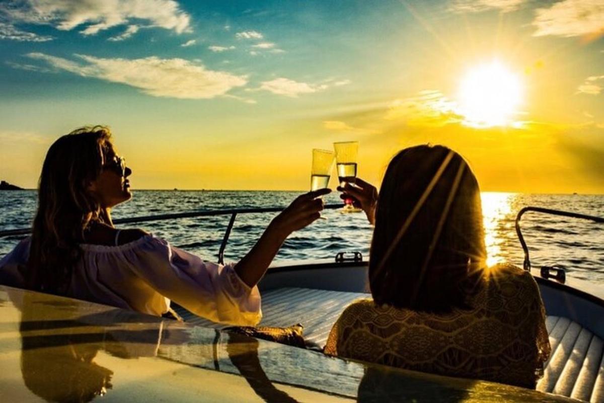 two women sitting on a boat taking a picture of the sunset