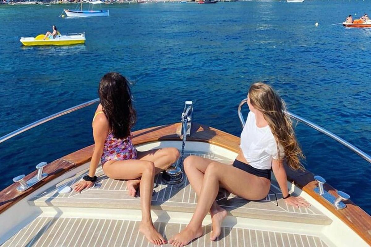 two women sitting on the back of a boat in the water