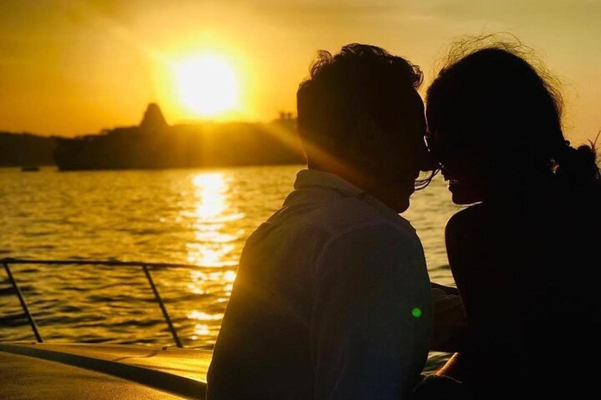 a man and a woman standing on a boat at sunset