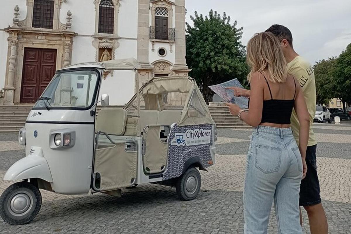 un uomo e una donna in piedi accanto a un piccolo veicolo