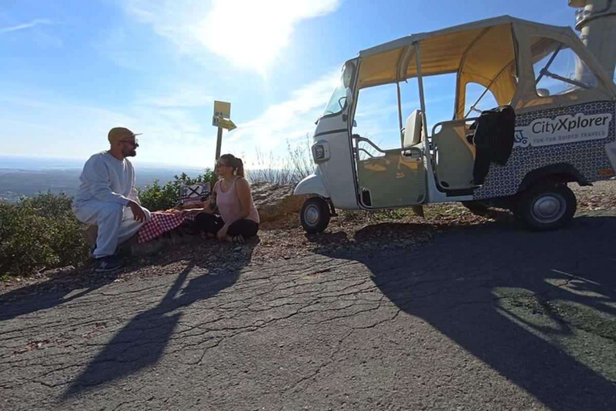 Un hombre y una mujer sentados junto a un carrito de golf.