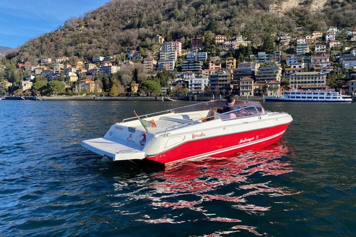 una barca rossa e bianca nell'acqua con una città