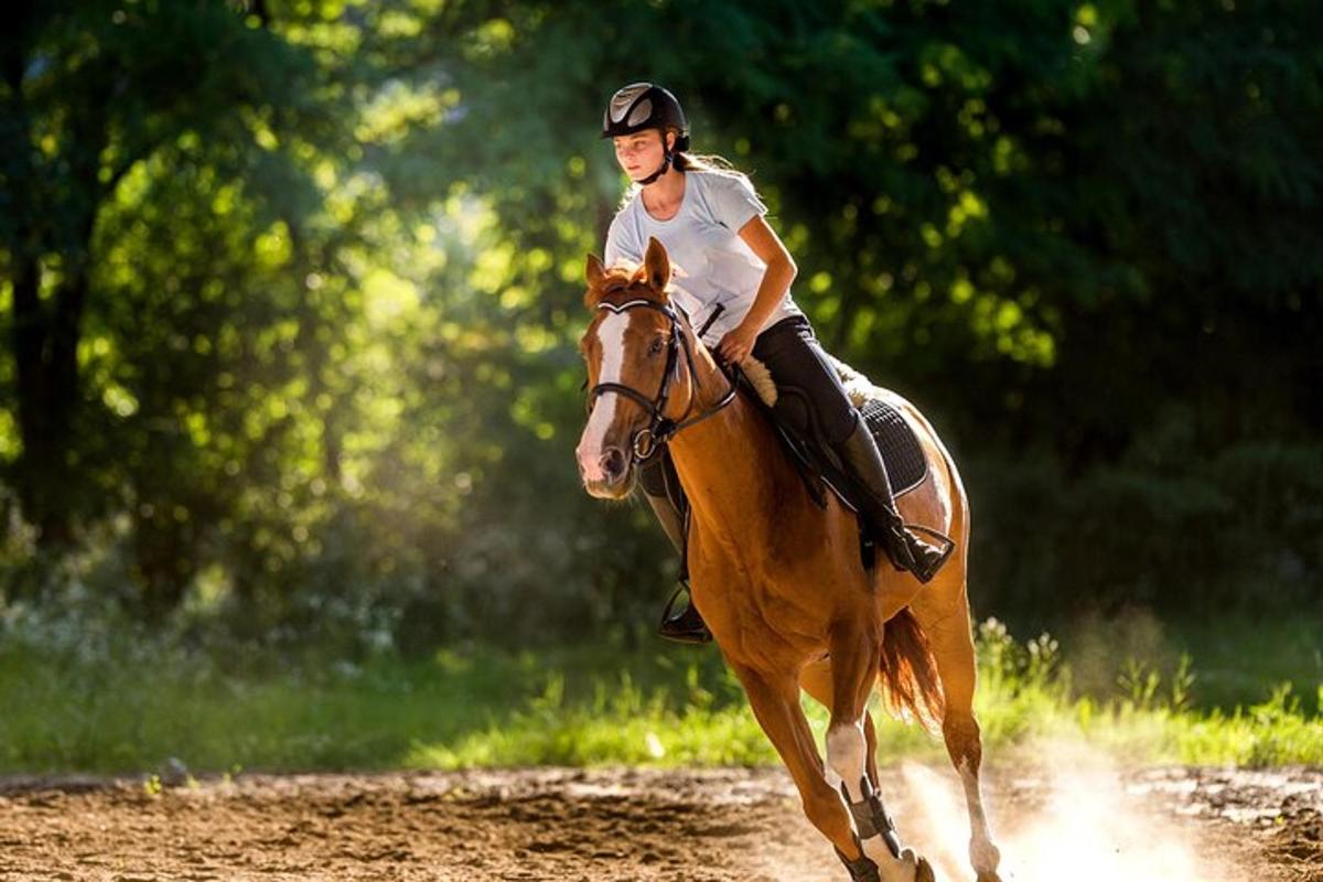 una mujer montando a caballo en un camino de tierra