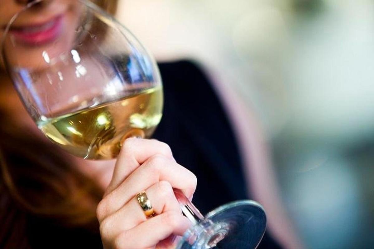 una mujer bebiendo una copa de vino blanco