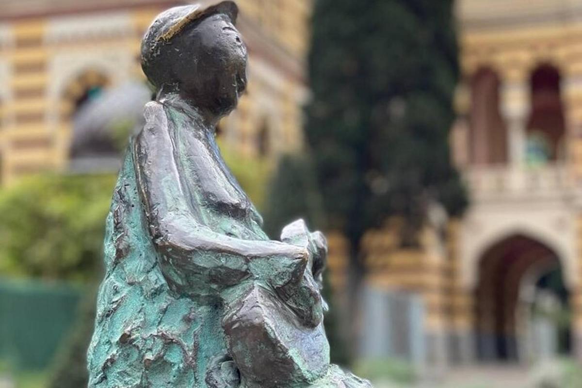 stytta af stúlku sem situr fyrir framan byggingu
