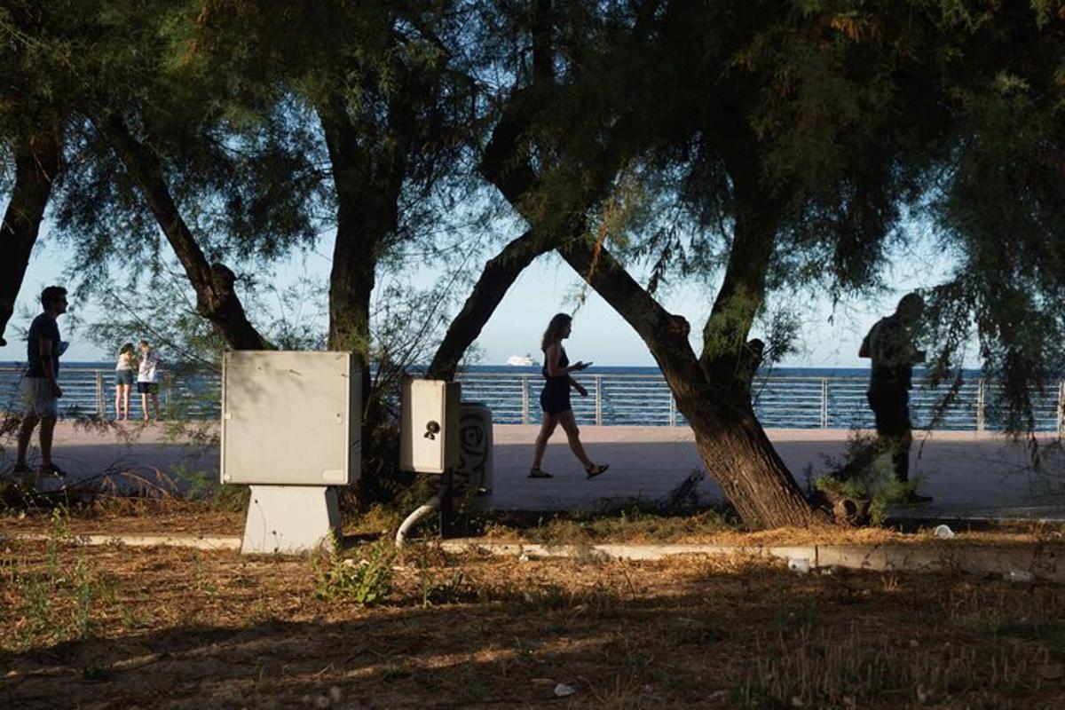 Ένα λευκό ψυγείο δίπλα σε δέντρα σε ένα πεζοδρόμιο