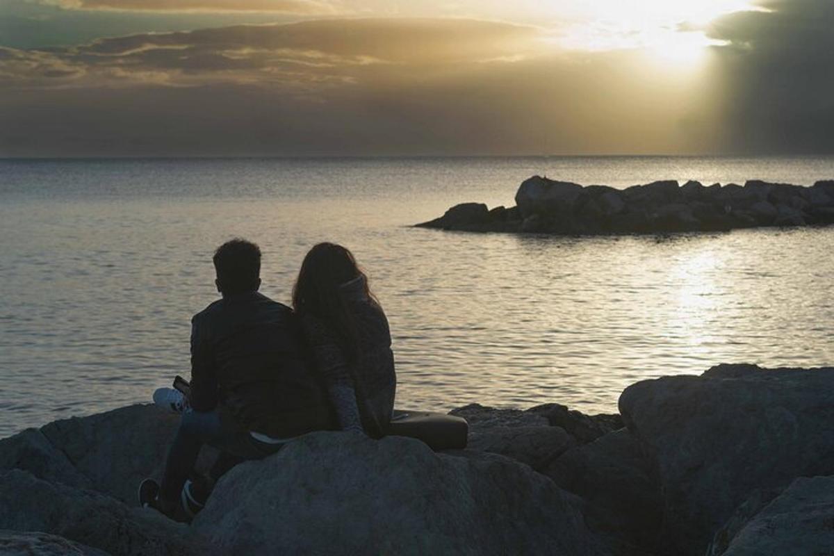 Ένας άντρας και μια γυναίκα κάθονται σε βράχους κοντά στο νερό