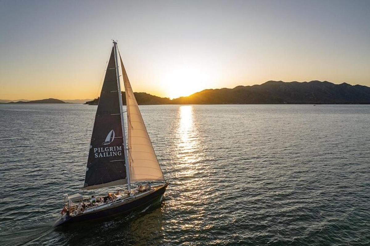 a small sail boat in the water at sunset