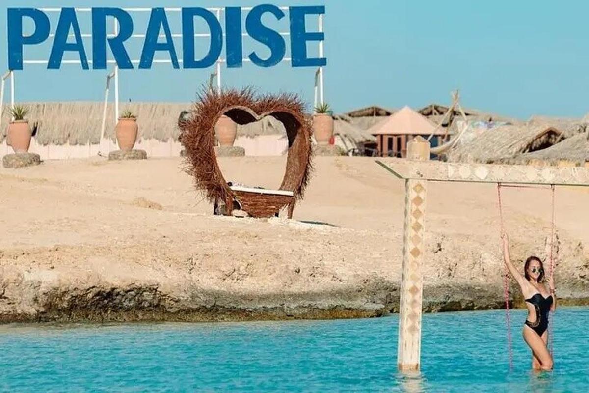 una dona en un gronxador a l'aigua amb les paraules paradís