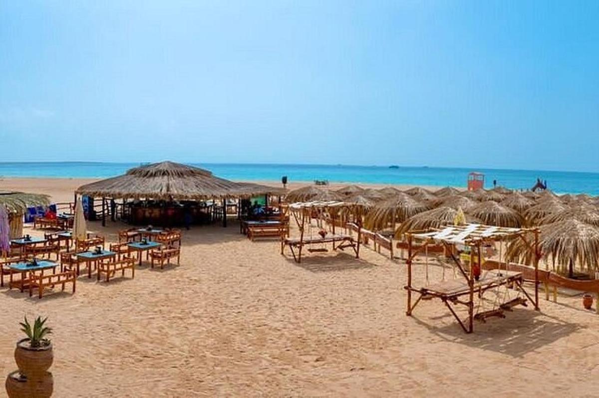 una platja amb taules, cadires i para-sols de palla