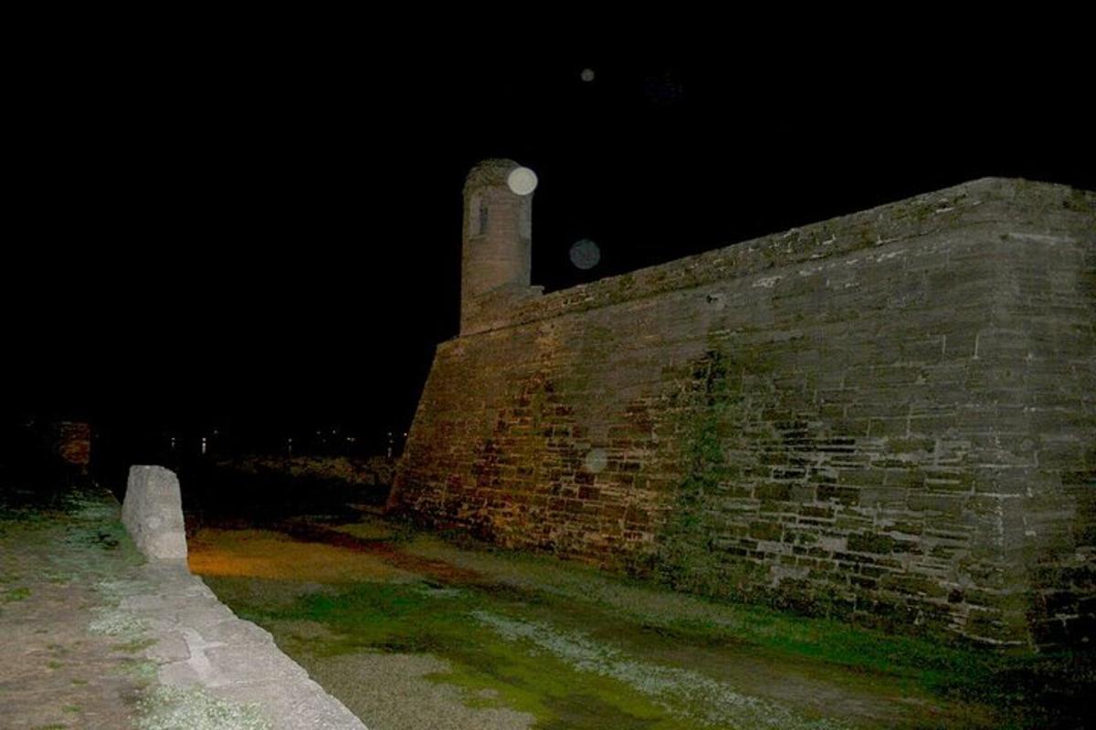 un vecchio muro di mattoni con una torre dell'orologio di notte