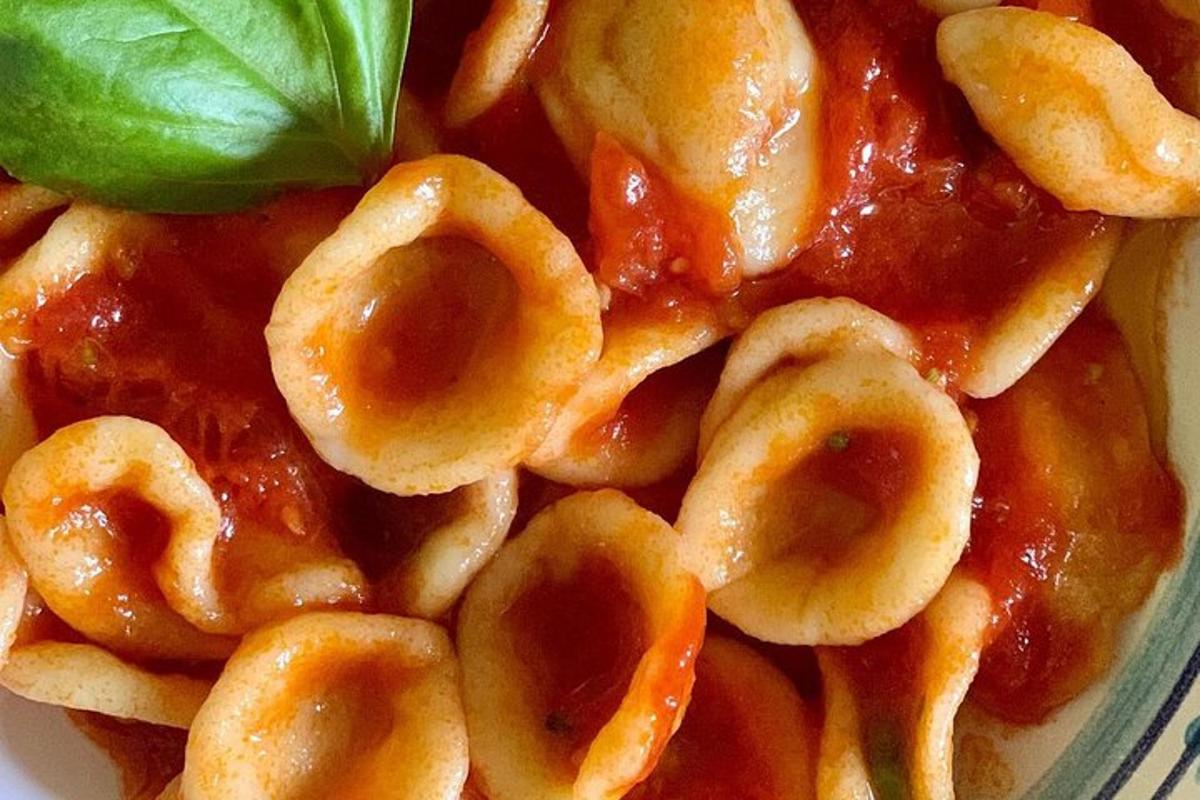 una ciotola di pasta con sugo e una foglia verde