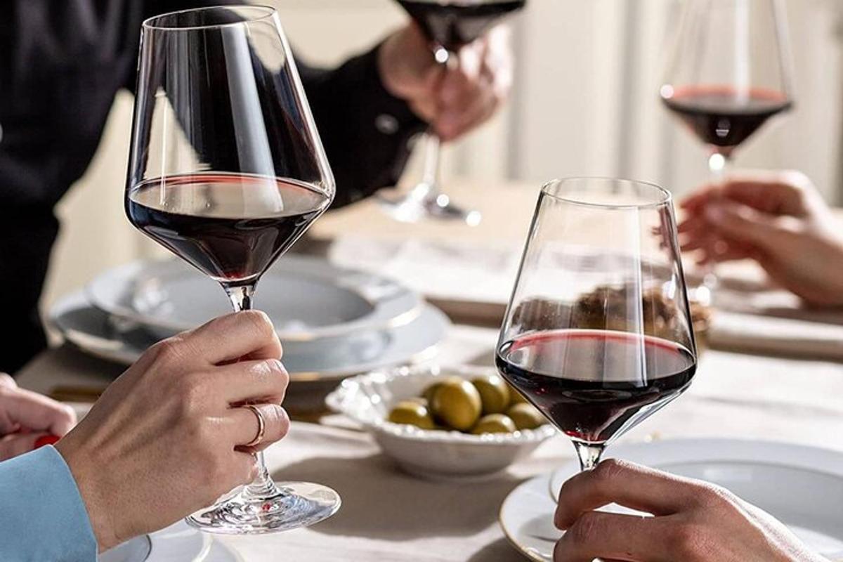un grup de persones assegudes a una taula amb copes de vi