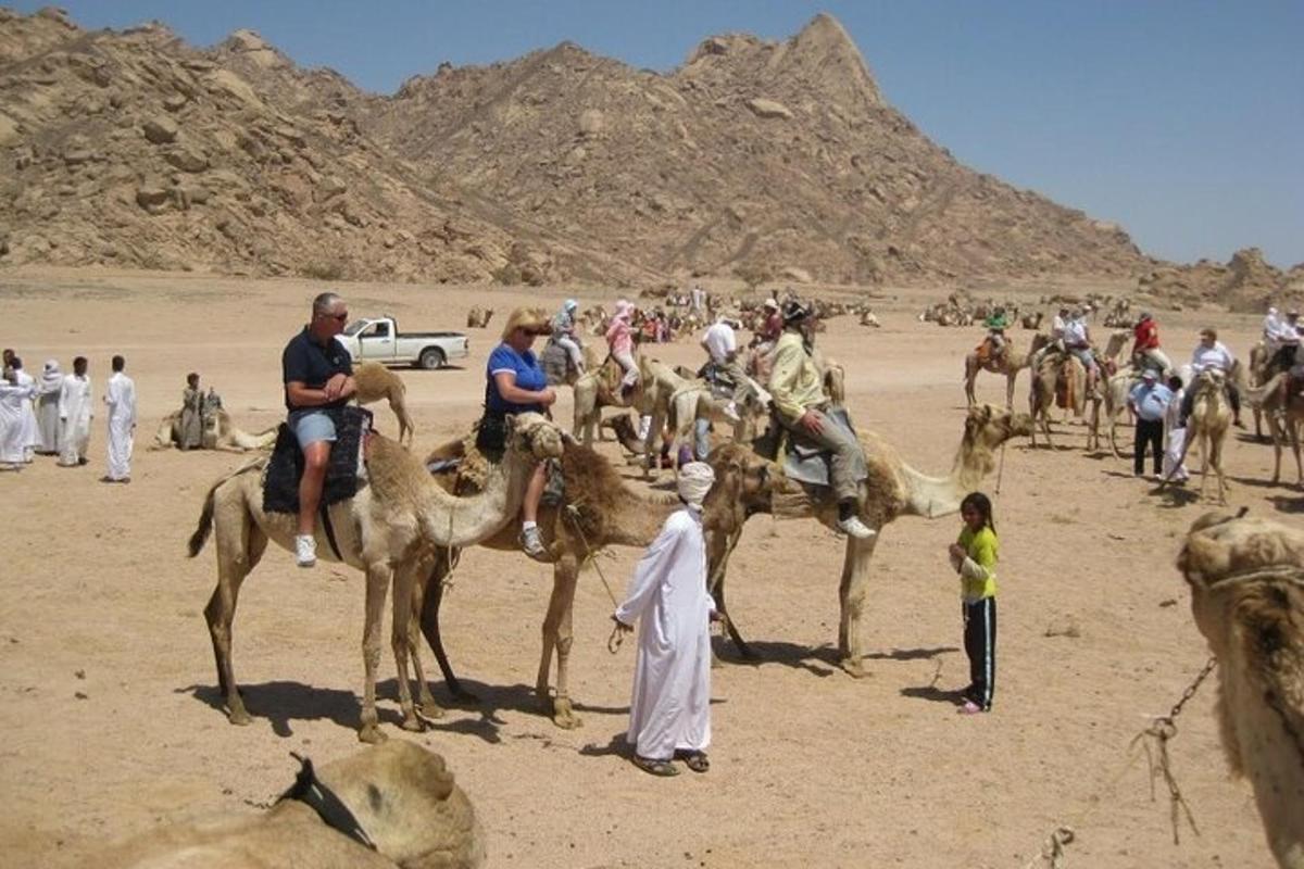 um grupo de pessoas andando de camelo no deserto