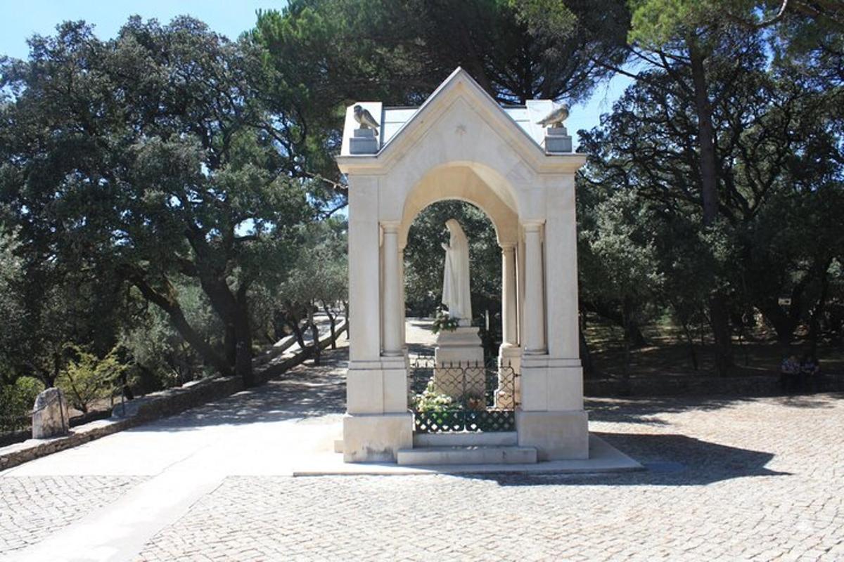 um arco branco em um parque com árvores ao fundo