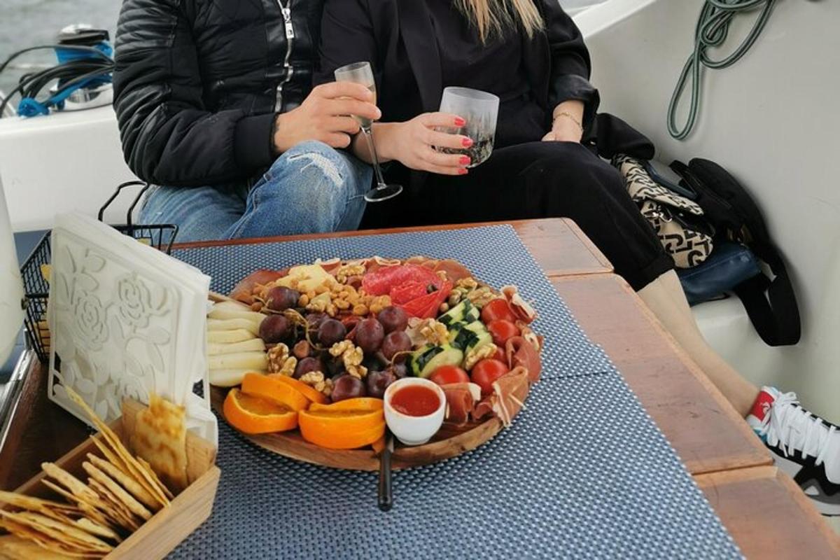 talíř jídla na stole se dvěma lidmi držícími nápoje