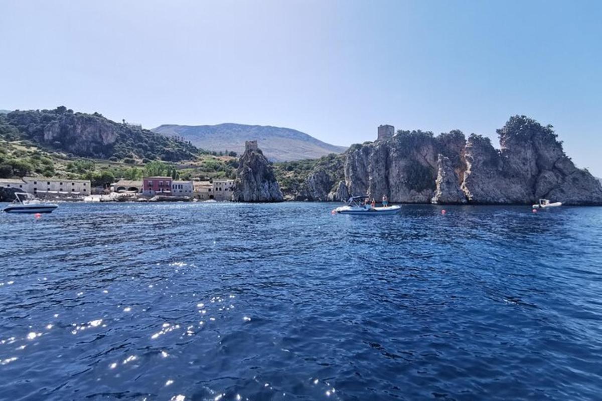 a group of boats in the water near a rocky island