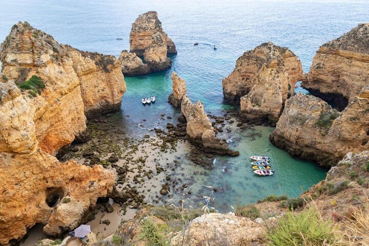 a group of boats in the water near some rocks