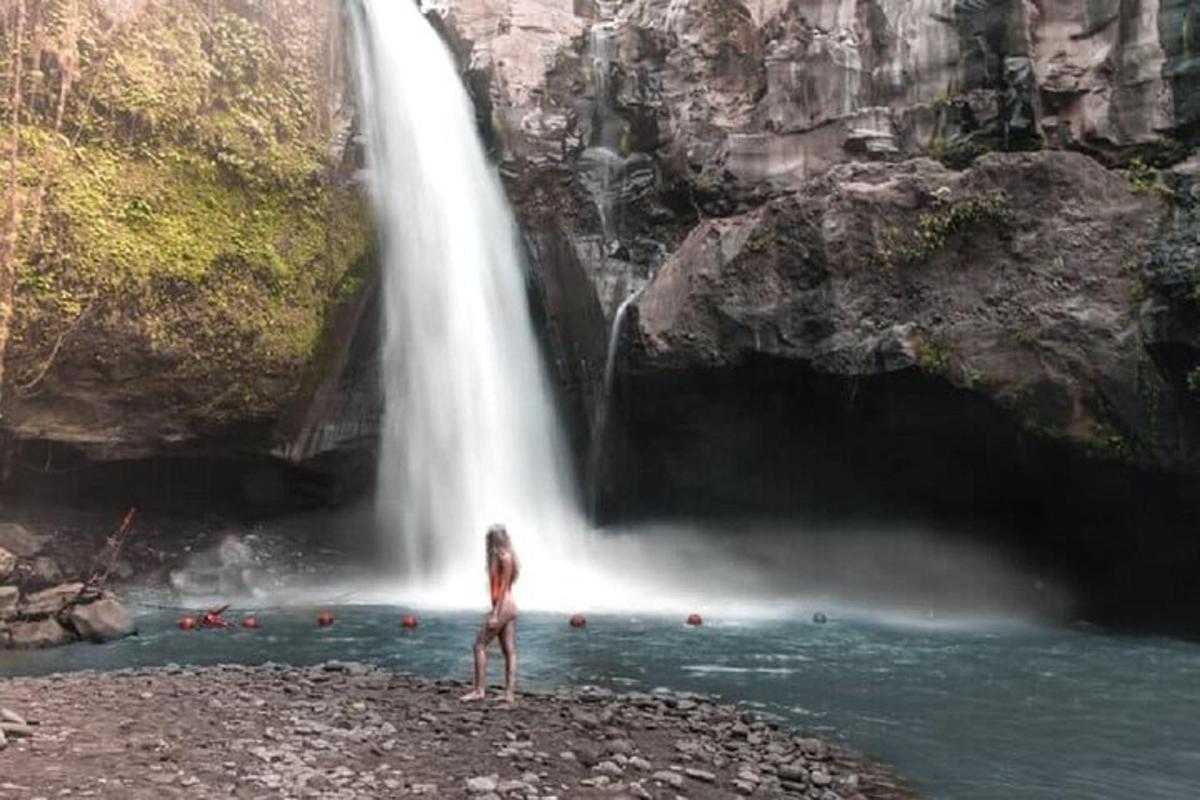 uma mulher parada em frente a uma cachoeira