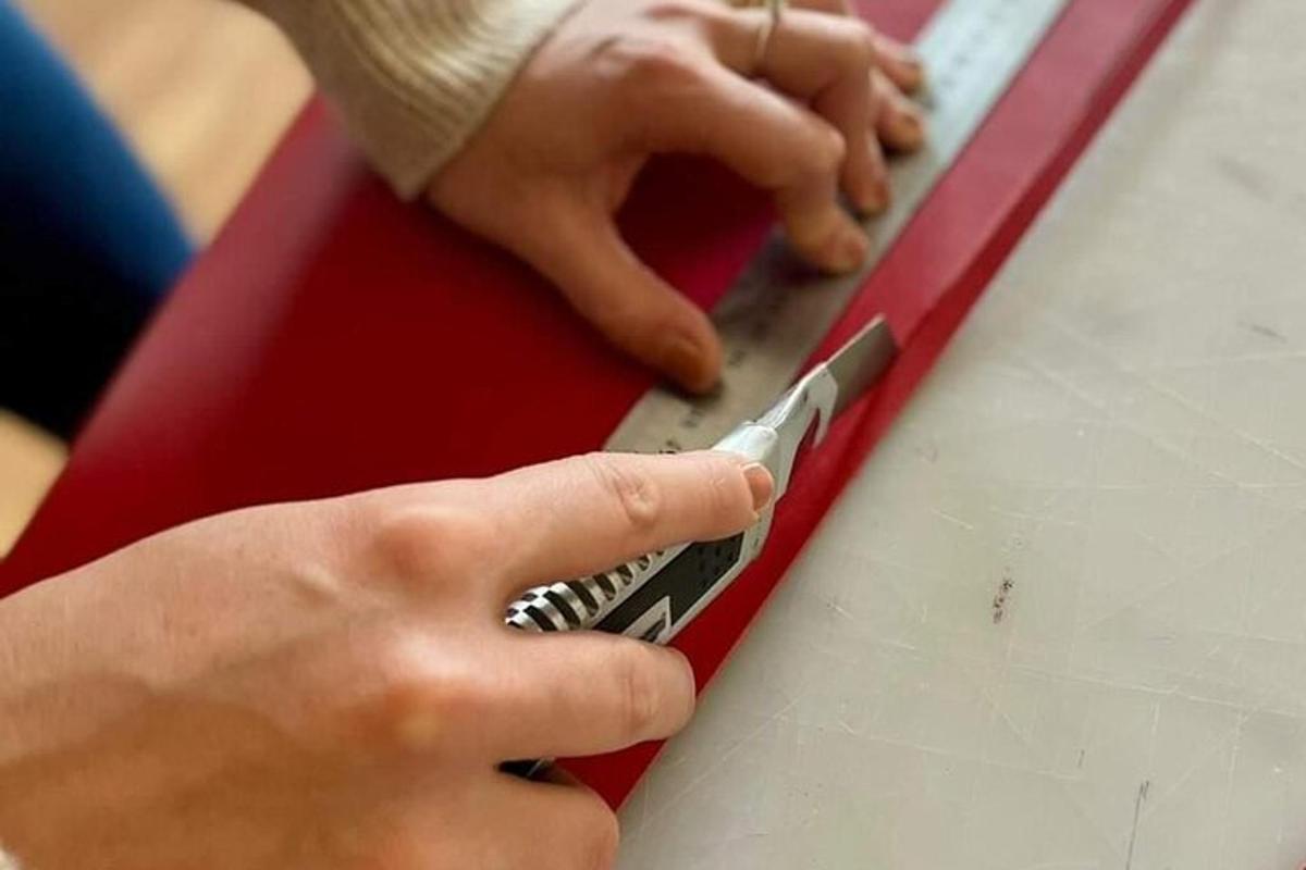 henkilö leikkaa paperiarkkia saksilla