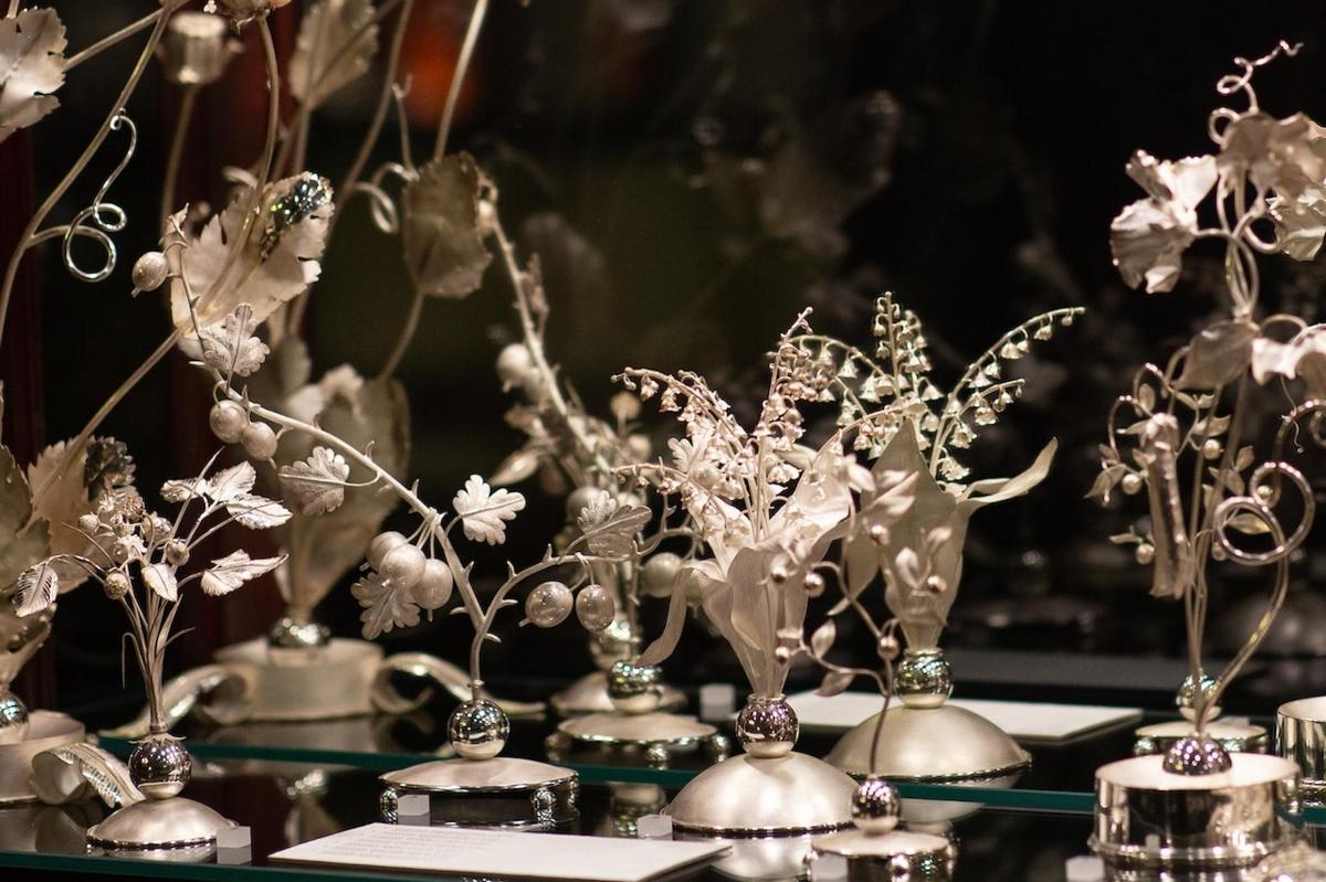 a group of silver vases on a table with flowers