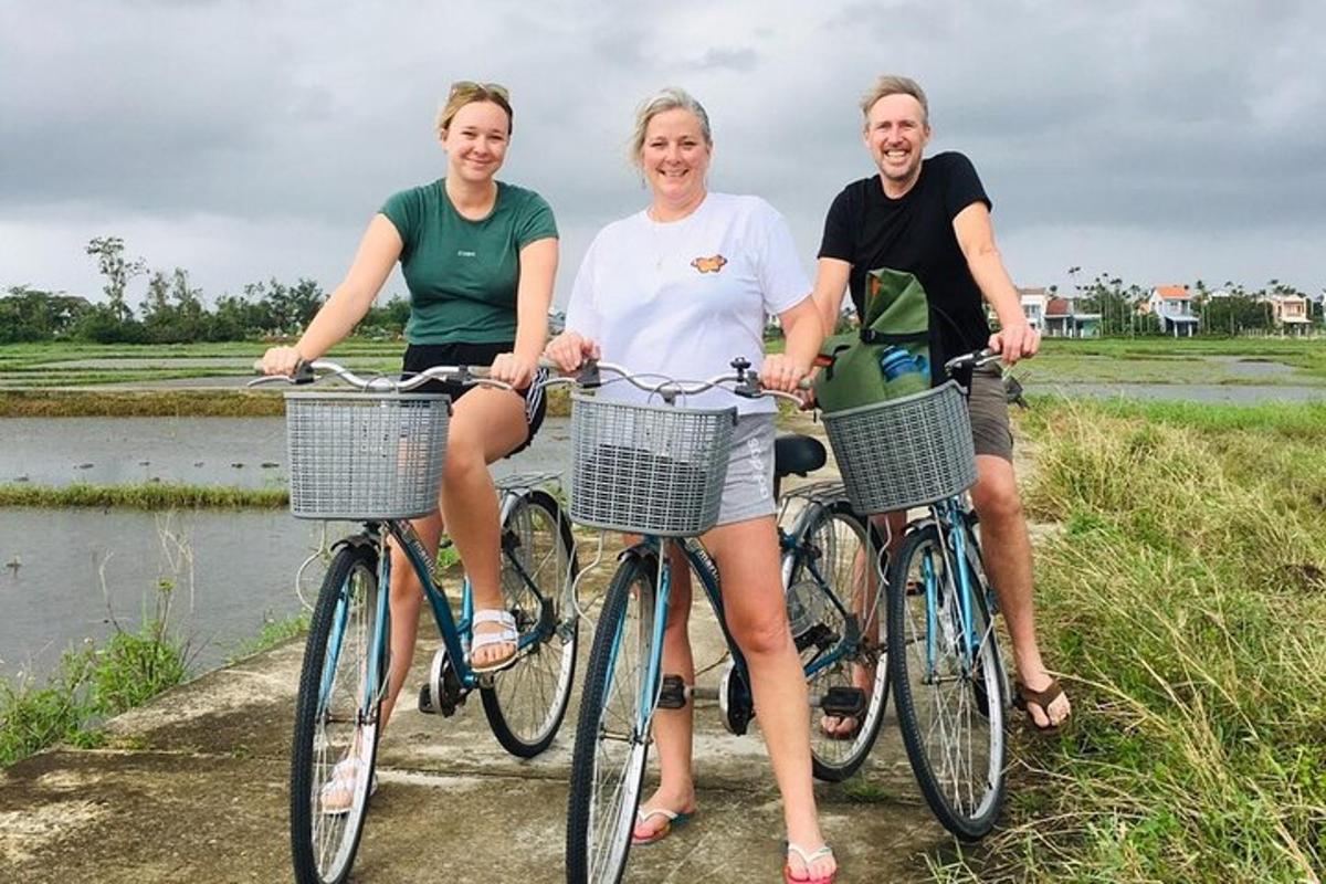 três pessoas sentadas em suas bicicletas ao lado de um rio