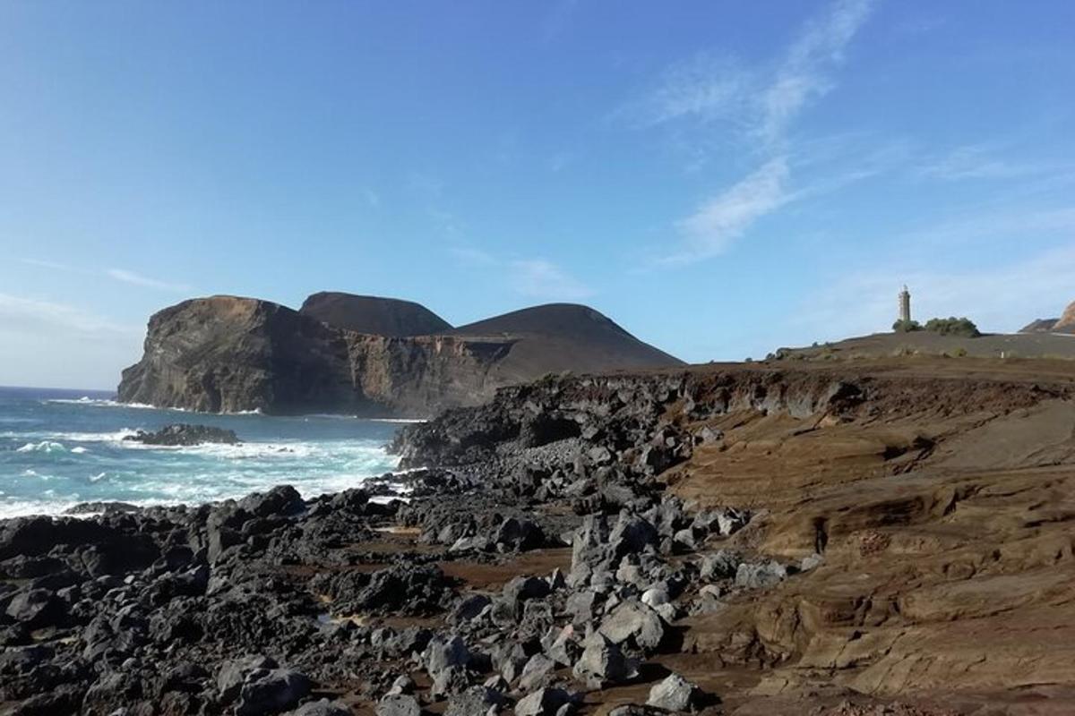 a rocky beach with a lighthouse and the ocean