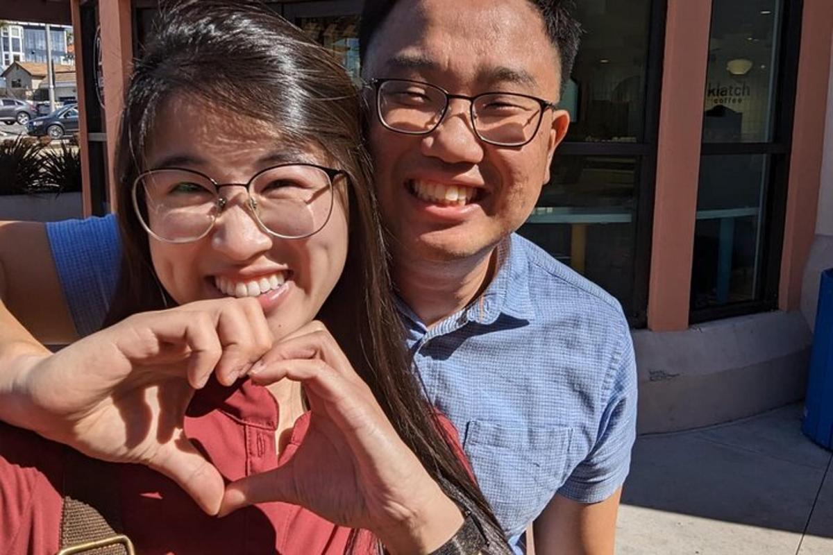 a man and woman making a heart with their hands