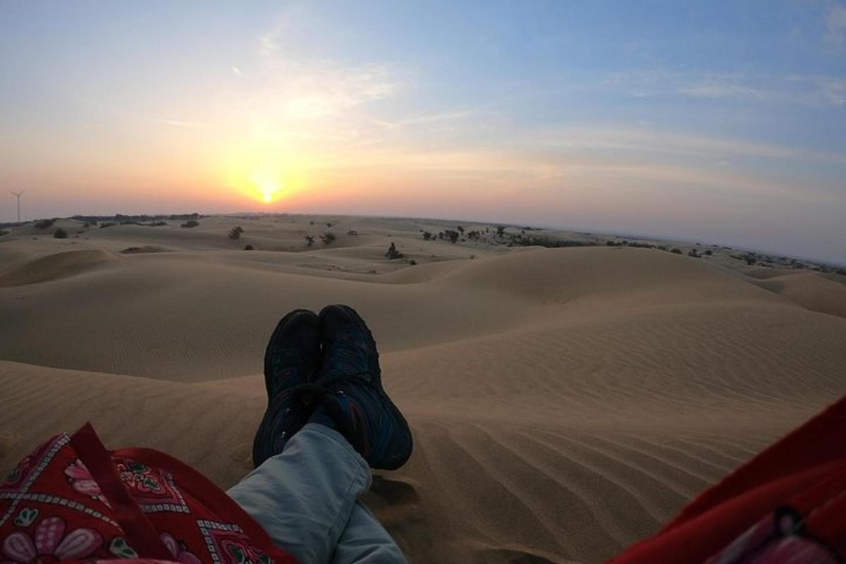 una persona seduta nel deserto che guarda il tramonto